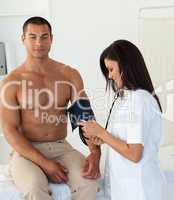 Smiling doctor checking the blood pressure of a patient