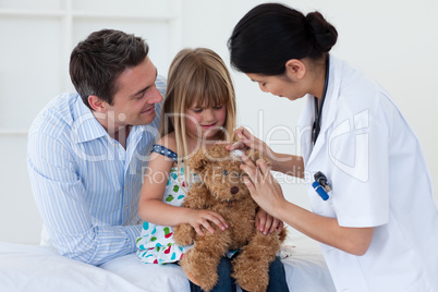 Portrait of a doctor and little girl examing a teddy bear
