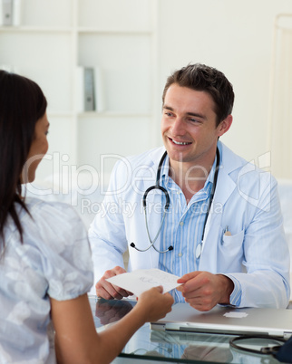 Smiling doctor giving a prescription to his female patient