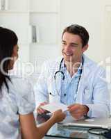 Smiling doctor giving a prescription to his female patient