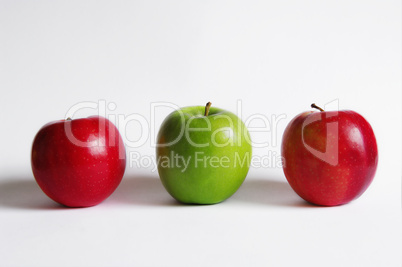 Zwei rote und ein grüner Apfel in der Reihe