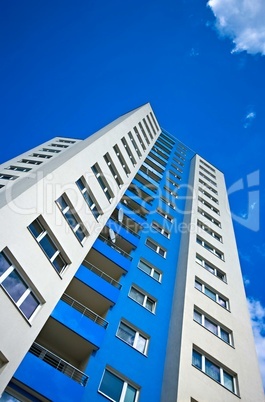 Hochhaus mit Fenstern und Balkon vor blauem Himmel