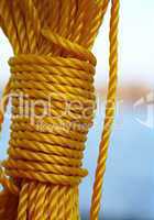 Gelbes Seil mit Knoten vor blauen Hintergrund