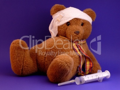 Kranker Teddy mit Verband und Spritze