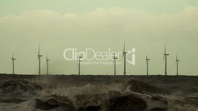 Low level shot of wind turbines at sea on a dark stormy day