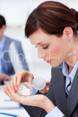 Portrait of a young businesswoman taking pills
