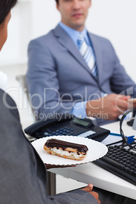 Close-up of a businesswoman carrying a pastry to her desk