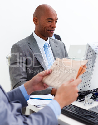 Smiling businessman working at a computer with his colleague rea