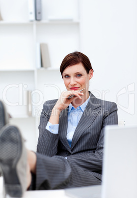 Satisfied Businesswoman sitting in office with feet on desk