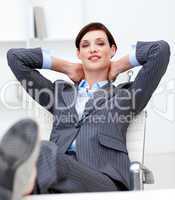 Businesswoman leaning back on a chair with his feet on the desk