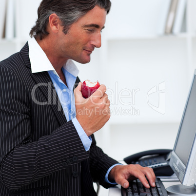 Close-up of a happy businessman eating a red apple