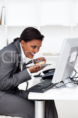 Young ethnic businesswoman eating a pastry