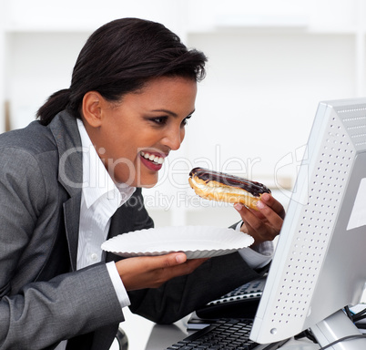 Close-up of a laughing businesswoman eating a chocolate eclair