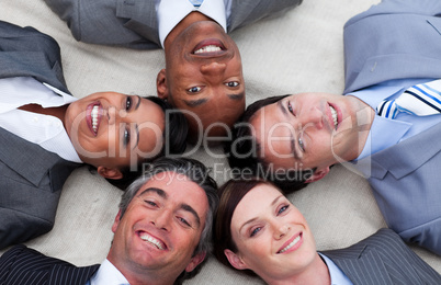 Multi-ethnic business team lying on the floor with heads togethe