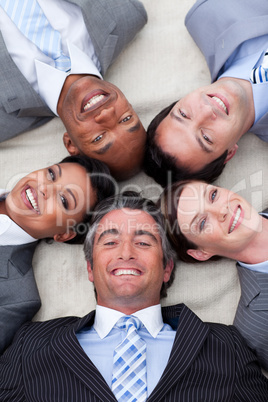 Smiling business team lying on the floor with heads together