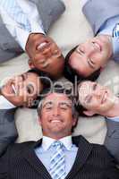 Smiling business team lying on the floor with heads together