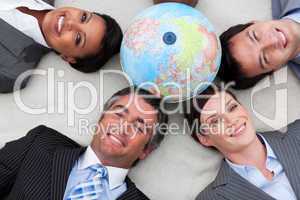 Business people lying on the floor around a terrestrial globe