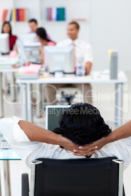 Businessman leaning back on a chair in front of his team