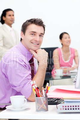 Attractive businessman smiling at the camera with his colleagues