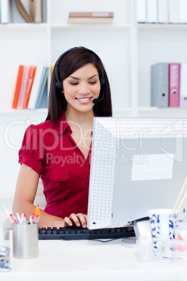 Smiling businesswoman with headset on at a computer
