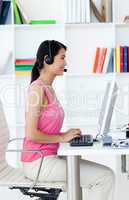 Serious businesswoman with headset on at a computer