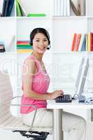 Asian businesswoman with headset on at a computer