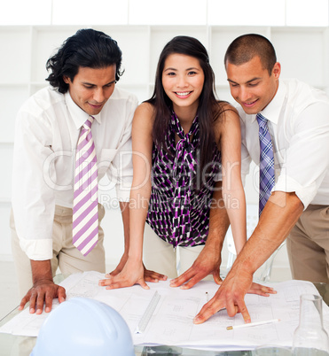 Close-up of a diverse group of engineers reviewing blueprints