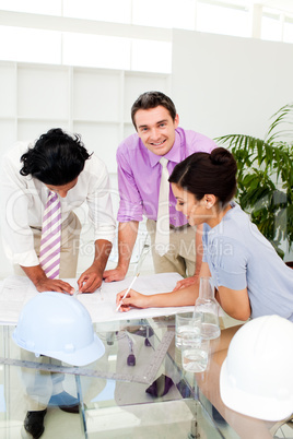 Multi-ethnic architect co-workers reviewing blueprints
