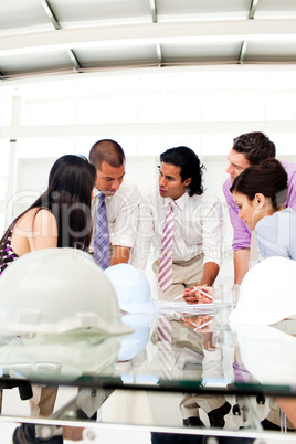 A group of engineers and their manager discussing blueprints