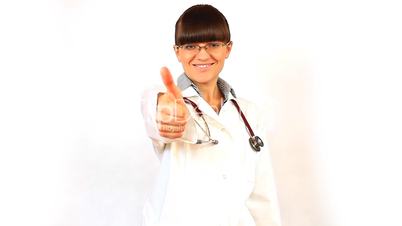 Young woman doctor in eyeglasses smiles and shows the thumb up