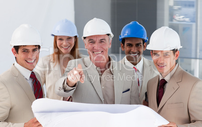 A group of smiling architects studying blueprints