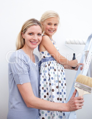 Happy mother and her daughter painting a wall