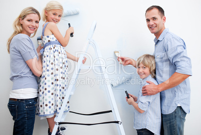 Happy family painting a room with brushes