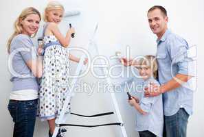 Happy family painting a room with brushes