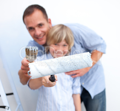 Close-up of a father and his son holding paintbrush