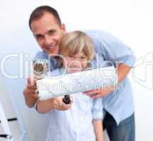 Close-up of a father and his son holding paintbrush