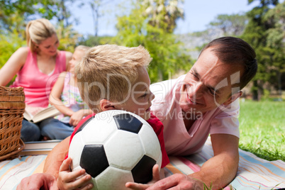 Father and son holding a soccer ball with their family reading i
