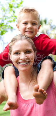 Close-up of a mother giving her son a piggyback ride in a park