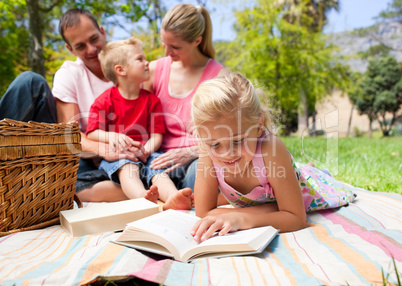 Serious little girl reading while having a picnic