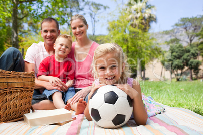 Little blond girl holding a soccer ball at a picnic