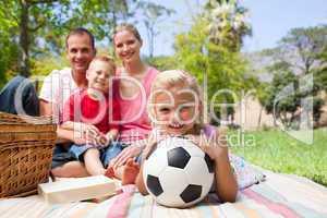 Little blond girl holding a soccer ball at a picnic