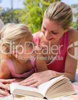 Portrait of a smiling mother and her daughter reading at a picni