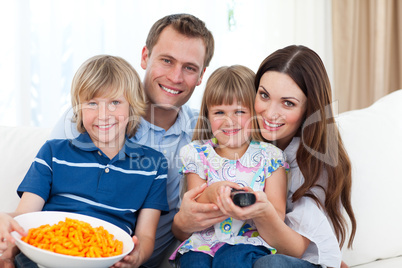 Happy family watching television and eating chips