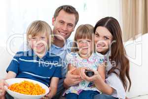 Happy family watching television and eating chips