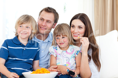 Family watching television and eating chips