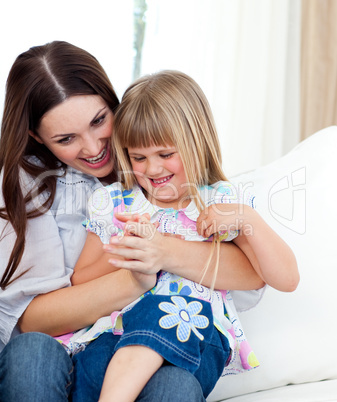 Cute girl sitting on her mother's lap celebrating a goal