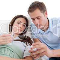 Husband giving pills to his wife with the flu