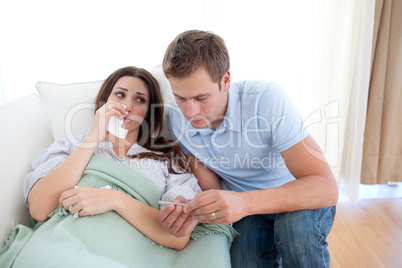 Man taking his wife temperature with a thermometer