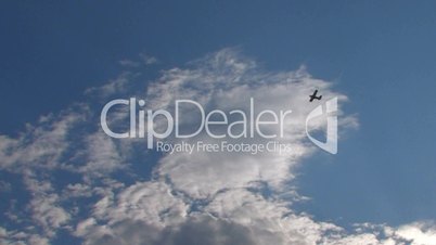 HD biplane flying high into the blue sky with clouds
