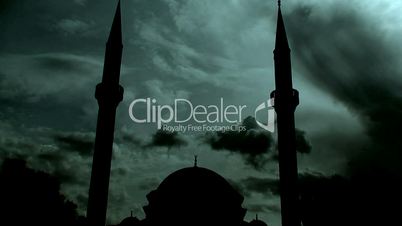 Time lapse clouds flowing past silhouetted twin minaret mosque 3